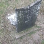 A damaged headstone at a grave site, illustrating the effects of time and the importance of remembrance